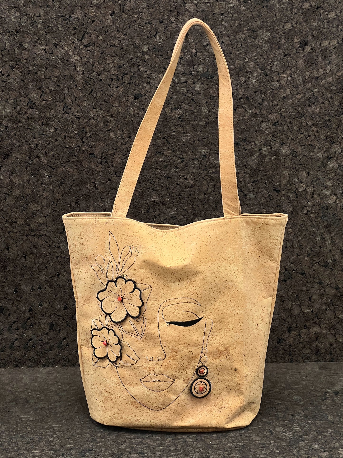 Découvrez l'élégance et l'originalité de ce cabas en cuir de liège éco-responsable, méticuleusement conçu par une talentueuse créatrice de Sardaigne. Ce sac arbore une magnifique broderie représentant le visage d'une femme entouré de fleurs, ajoutant une touche artistique et féminine. À l'intérieur, vous trouverez une doublure en tissu délicat, offrant une protection douce à vos effets personnels.