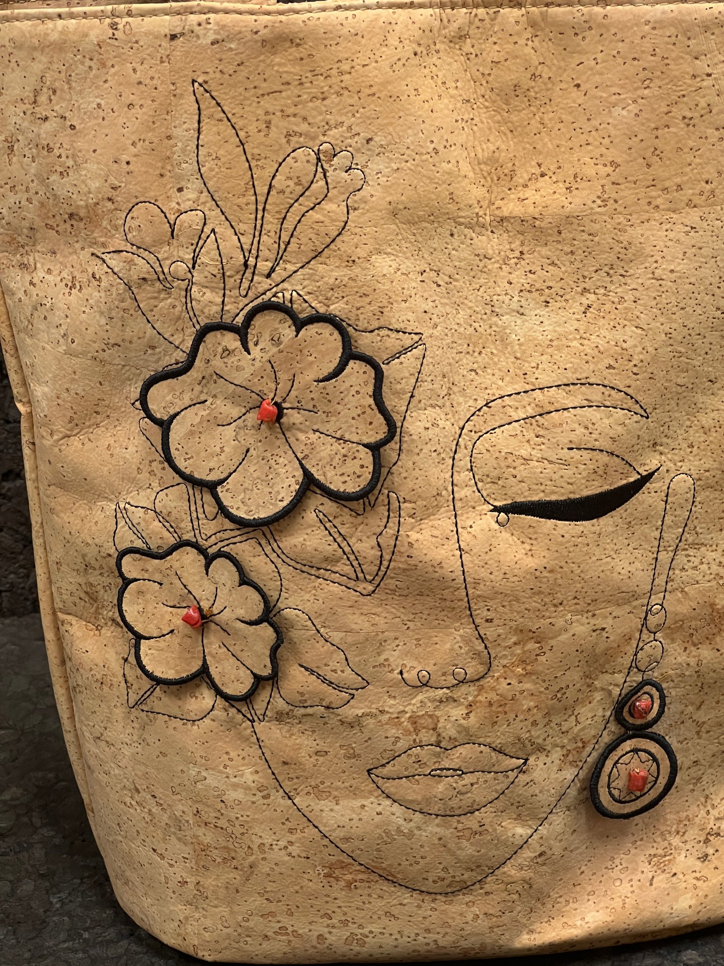 Découvrez l'élégance et l'originalité de ce cabas en cuir de liège éco-responsable, méticuleusement conçu par une talentueuse créatrice de Sardaigne. Ce sac arbore une magnifique broderie représentant le visage d'une femme entouré de fleurs, ajoutant une touche artistique et féminine. À l'intérieur, vous trouverez une doublure en tissu délicat, offrant une protection douce à vos effets personnels.