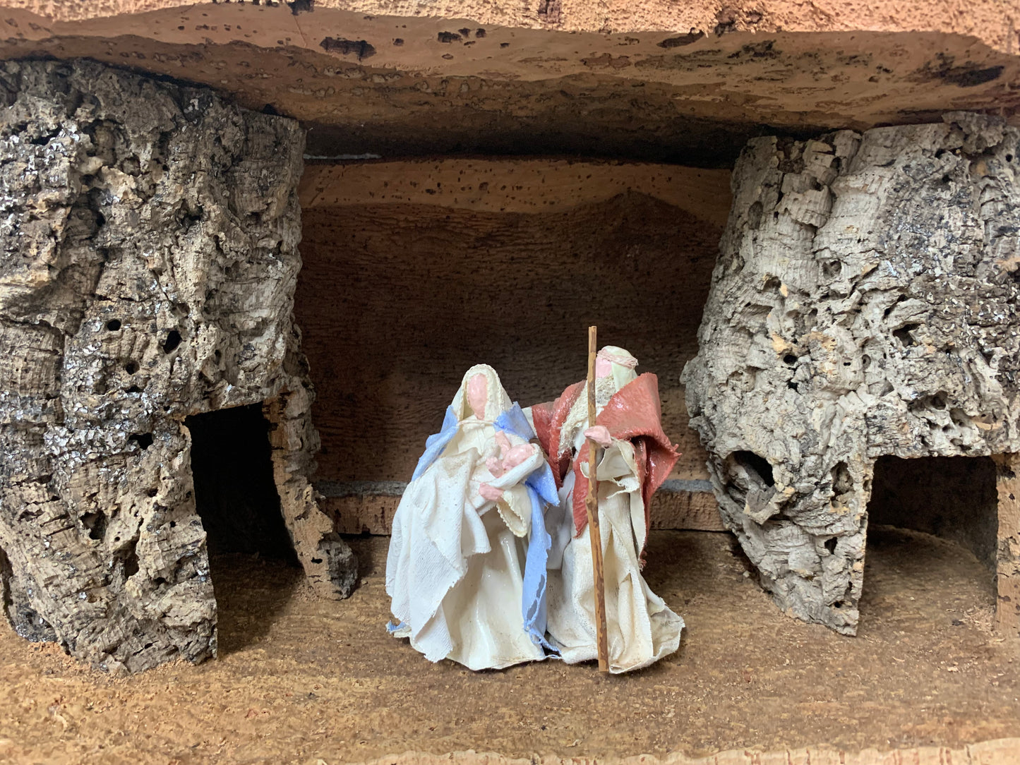 Crèche en liège avec Marie et Joseph portant Jésus, un petit puits se trouve sur le côté zoomé sur les personnages