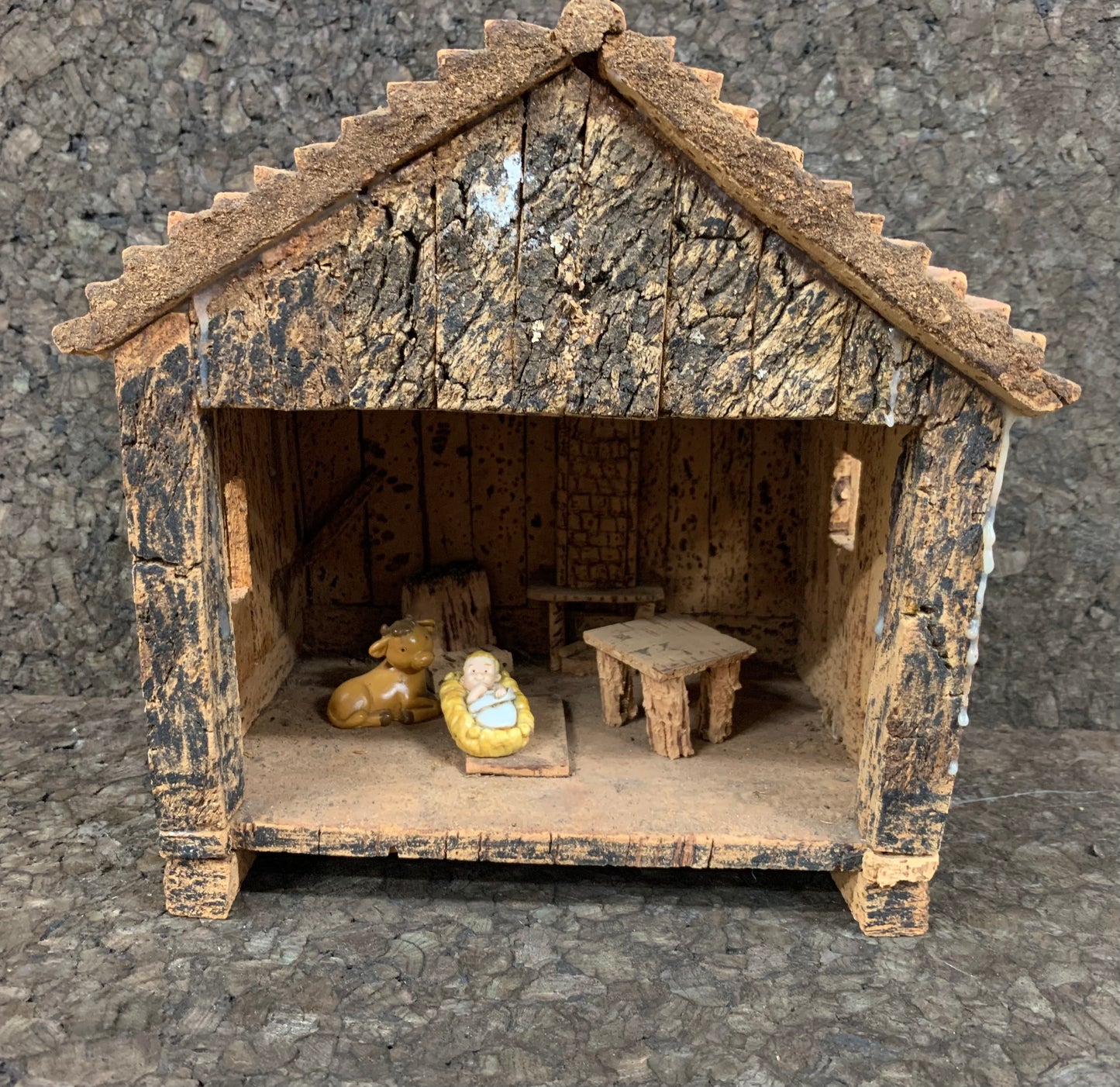 Crèche en forme de maisonette en liège et en bois représentant Jésus et le boeuf, accompagné de petits meubles en liège et bois